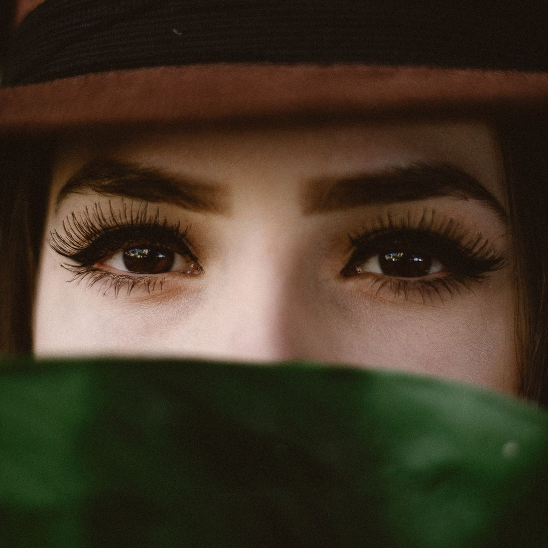 Woman's eyes peeking out from under a hat brim