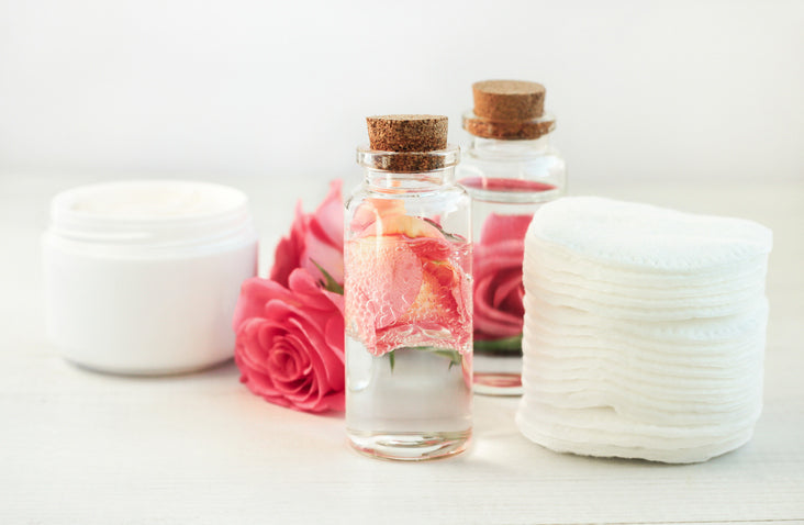 bottles of rosewater next to cosmetic pads